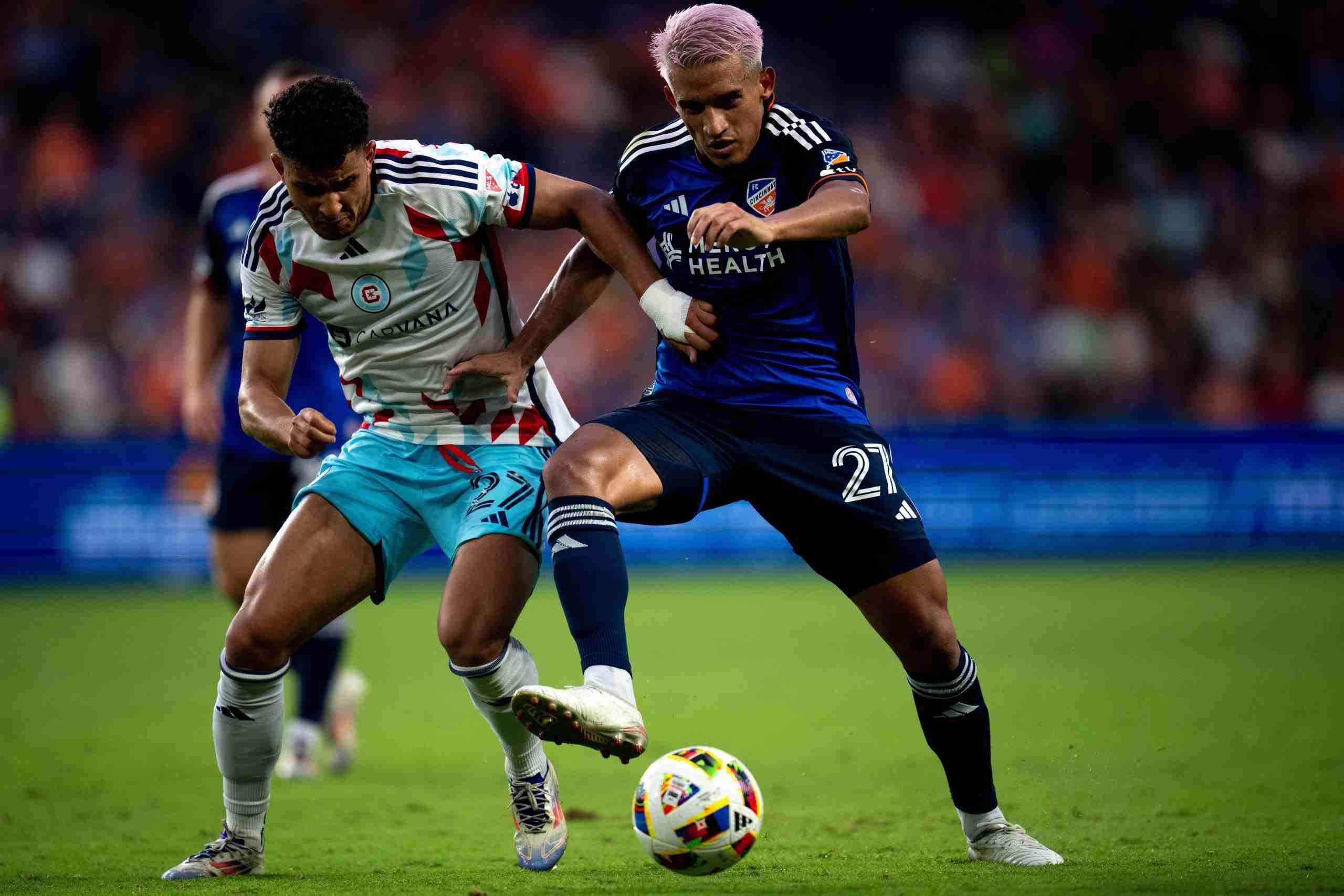 FC Cincinnati midfielder Yamil Asad (27) and Chicago Fire defender Allan Arigoni (27) compete for the ball in the second half of the MLS match at TQL Stadium in Cincinnati on Wednesday, July 17, 2024.